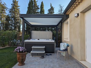 Un espace extérieur abrité avec des sièges, un banc, un jacuzzi et une petite table.