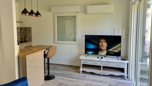 A modern living room with a flat-screen TV, a wooden dining table, and a blue sofa.
