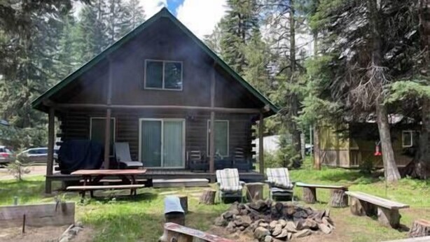 A cabin with a porch, a fire pit, and outdoor seating.