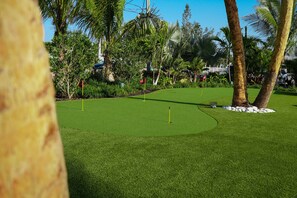 Un parcours de golf avec un gazon bien entretenu, des palmiers et un ciel dégagé.