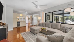 A modern living room with a sectional sofa, a coffee table, and a TV on a stand.