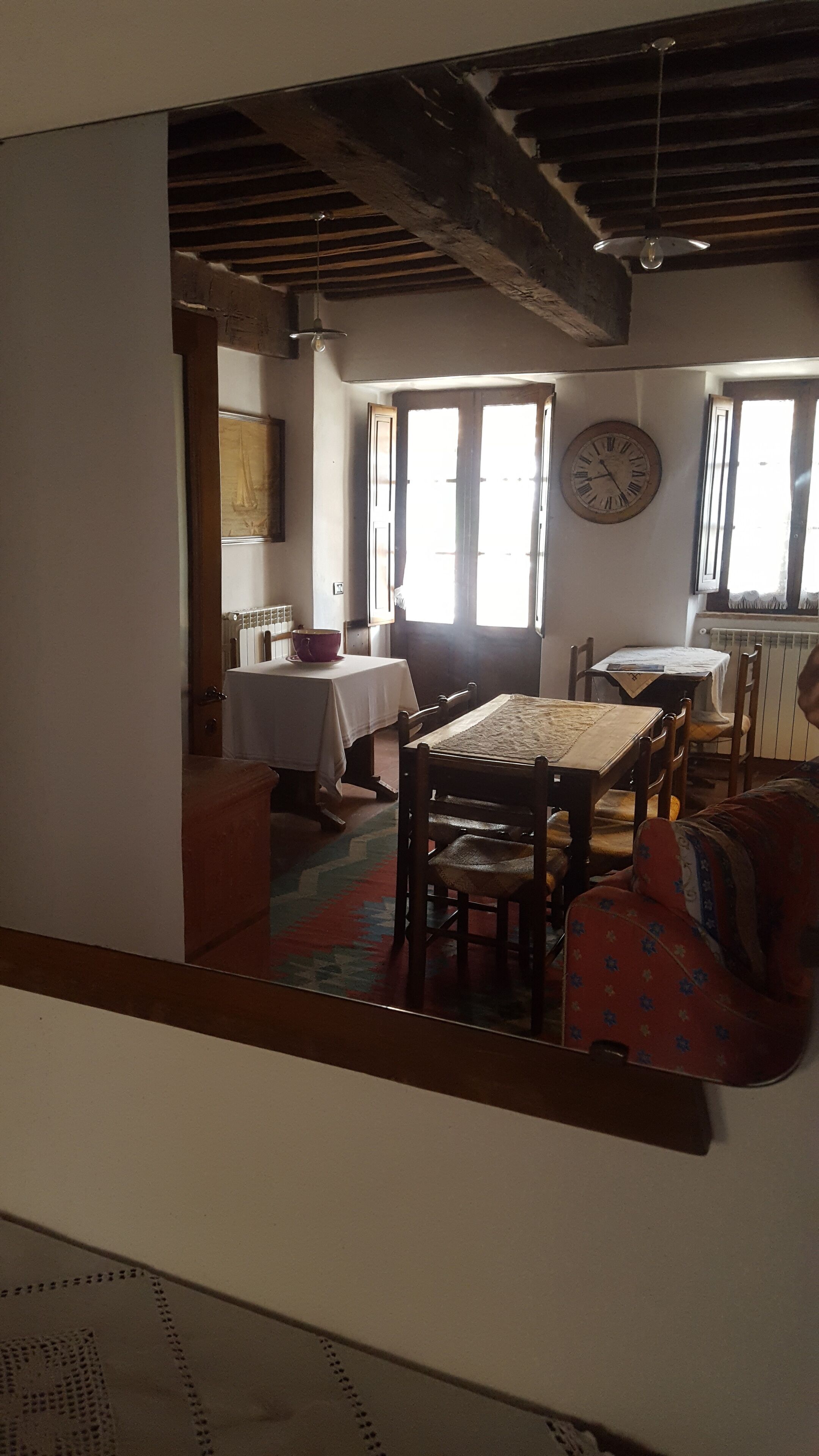 A dining area with a table and chairs, a clock on the wall, and a window with curtains.