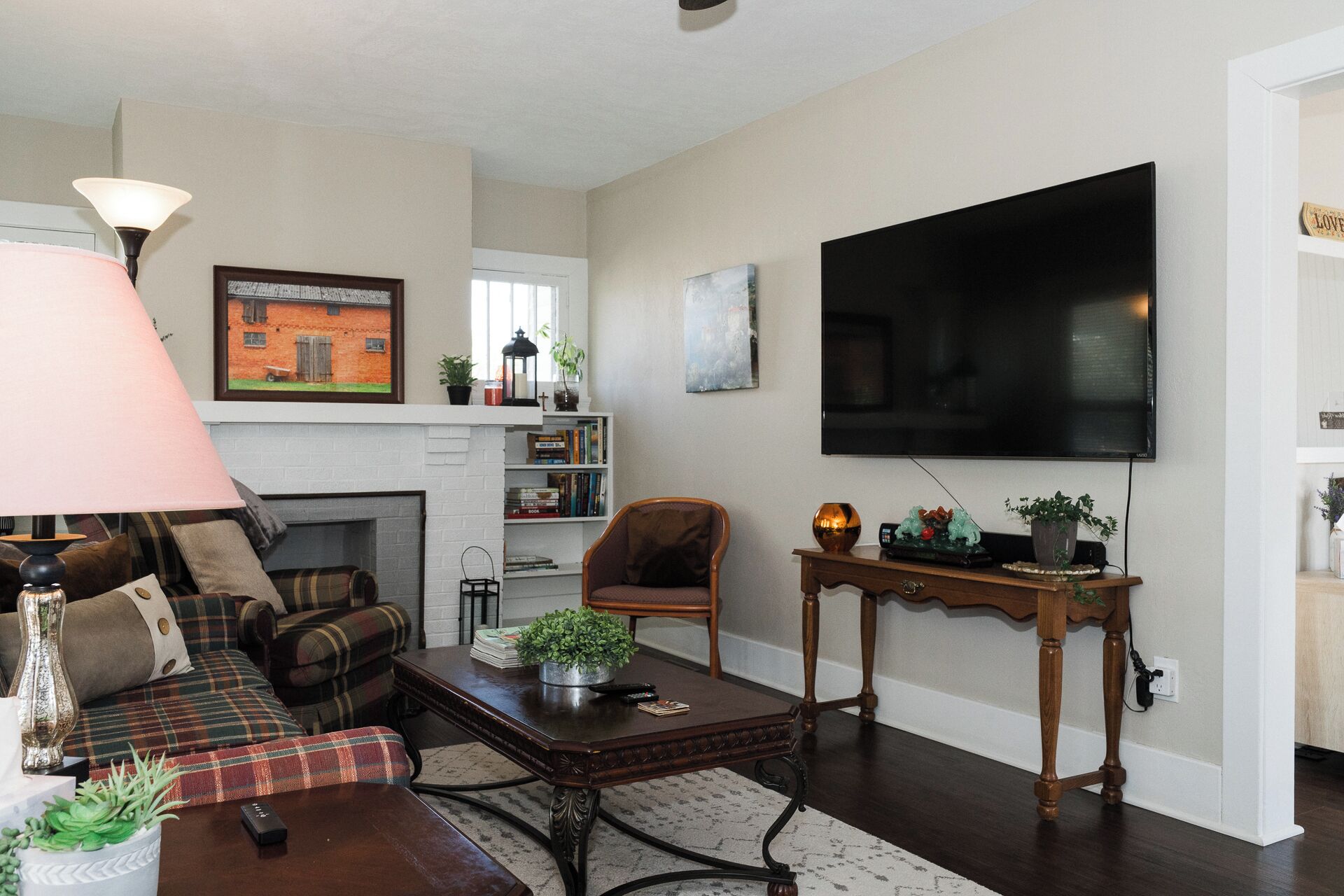 Una sala de estar con chimenea, televisor montado en la pared, sofá, mesa de centro y lámpara.