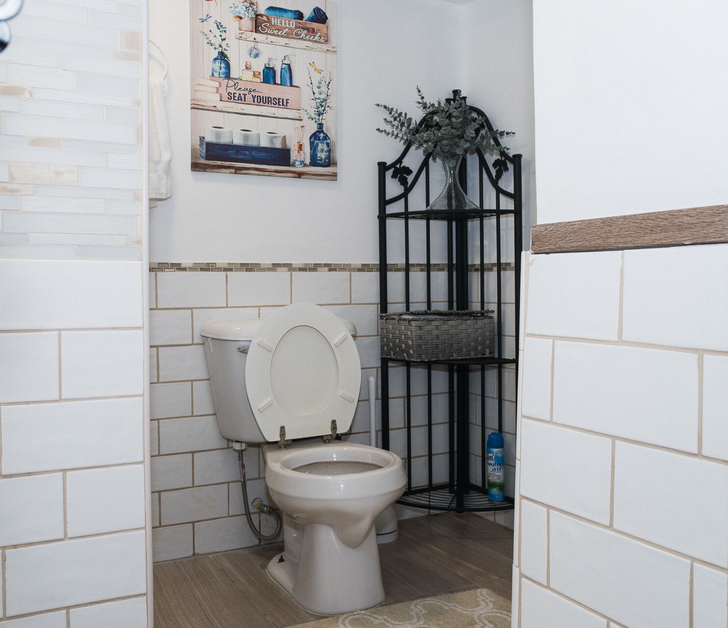 A bathroom with a toilet, a shelf with toiletries, and a decorative sign.