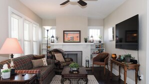 Una sala de estar con chimenea, un sofá, una mesa de centro y un televisor montado en la pared.
