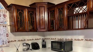 Een keuken met donkere houten kasten, een wit aanrecht, een magnetron en een koffiezetapparaat.