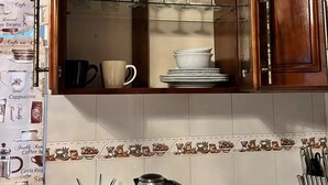 Een keuken met een houten kastje met wijnglazen, borden en een koffiezetapparaat.