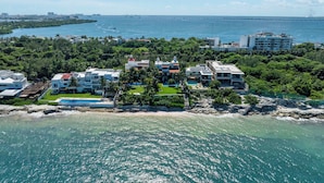 An aerial view of a coastal resort with multiple buildings, a swimming pool, and a beachfront. - Villa del Sol | 6BR | Exclusive Family Retreat (Cancún)