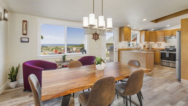 A modern kitchen with wooden cabinets, a stainless steel refrigerator, and a large island with seating. - Experience Sequim Charm & Amazing Lighthouse Views, by the Olympic National Park (Sequim)