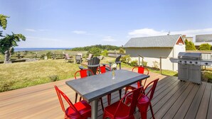An outdoor deck with a table and chairs, a grill, and a view of the sea. - Experience Sequim Charm & Amazing Lighthouse Views, by the Olympic National Park (Sequim)