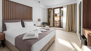 Habitación de hotel moderna con una cama grande, cabecera de madera, una mesita de noche, una silla y una puerta corrediza de vidrio que da a un espacio exterior.