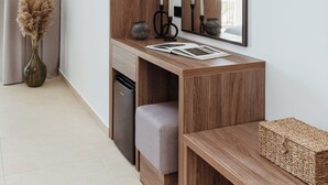 Una habitación moderna con un escritorio de madera, un espejo, un televisor y una pequeña zona de estar.