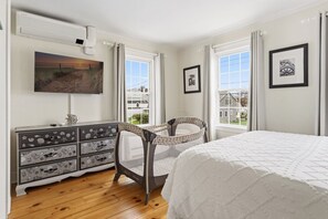 A bedroom with a bed, dresser, chair, and a TV on the wall. - Historic Home, Walk to Seaport & Downtown (Stonington)