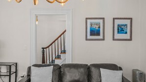 A living room with a leather sofa, a chandelier, and two framed pictures on the wall.