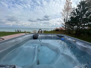 Ett bubbelbad med utsikt över havet och en gräsyta med stolar.