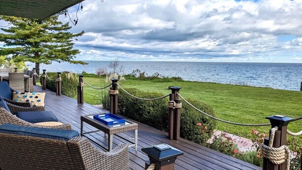 A wooden deck with outdoor furniture, a view of the sea, and a rope barrier. - Sheridan Shores Escape - Hot Tub w Amazing Views! (Lexington Township)