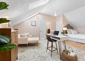 Un dormitorio cálido y luminoso en un ático, con un escritorio, un sofá cómodo y una cama.