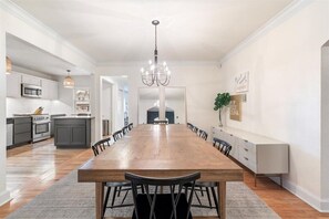 Un comedor amplio con una larga mesa de madera, sillas negras y un candelabro.