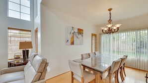 A dining area with a glass table and chairs, a chandelier, and artwork on the walls. - Lake Elsinore Vacation Rental ~ 4 Mi to the Lake! (Lake Elsinore)