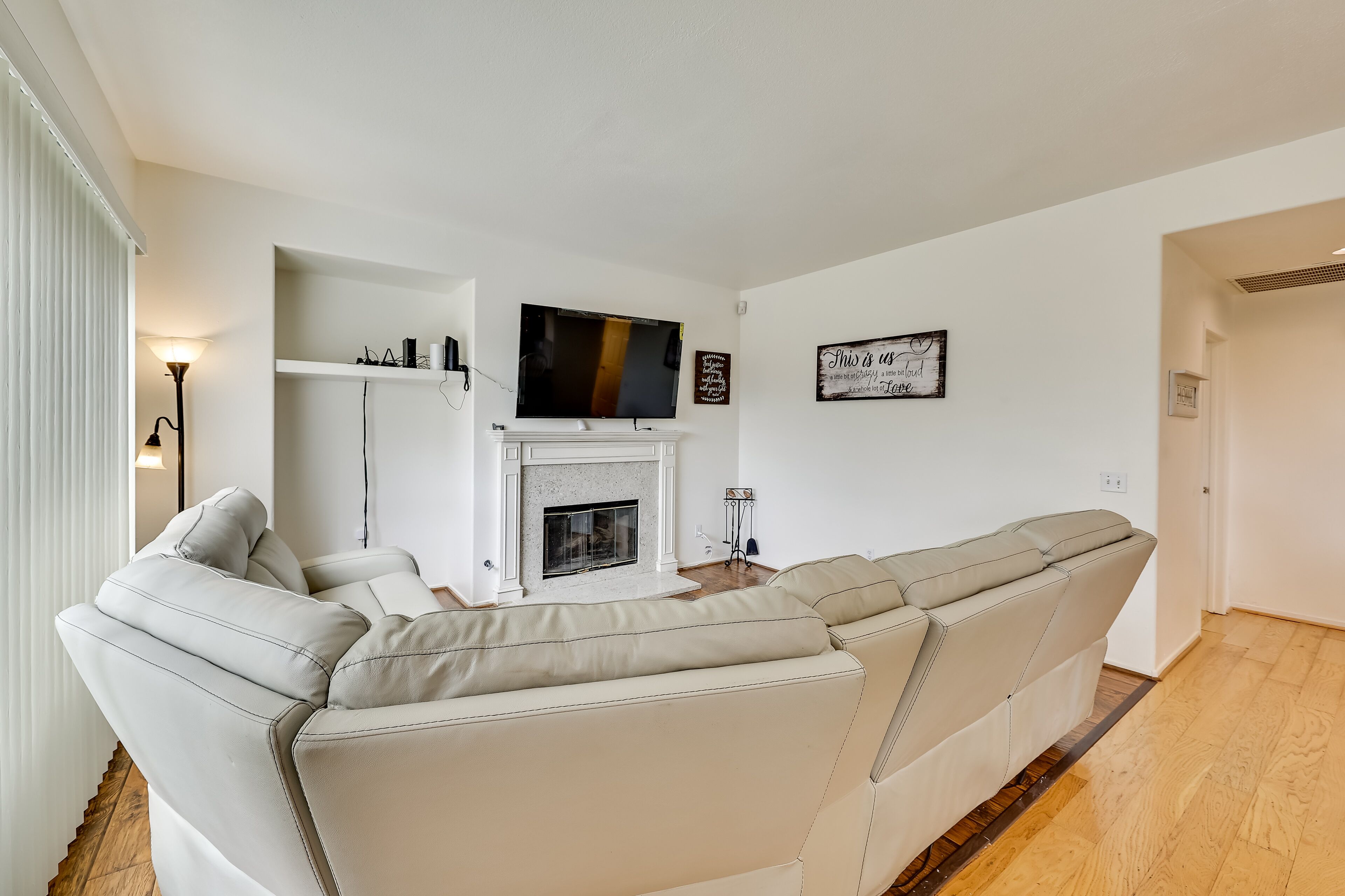 A modern living room with a sectional sofa, a flat-screen TV, a fireplace, and minimalist decor.