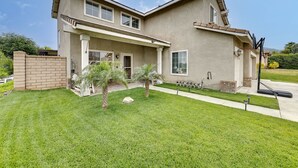 A two-story house with a covered patio, a brick wall, and a well-maintained lawn. - Lake Elsinore Vacation Rental ~ 4 Mi to the Lake! (Lake Elsinore)