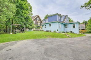 Un quartier résidentiel avec une maison bleue, un patio couvert et une pelouse bien entretenue.