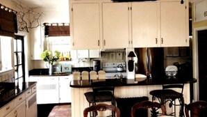 A kitchen with white cabinets, a black countertop, and a central island with bar stools.