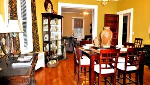 A dining area with a wooden table and chairs, a chandelier, and a glass cabinet with decorative items.