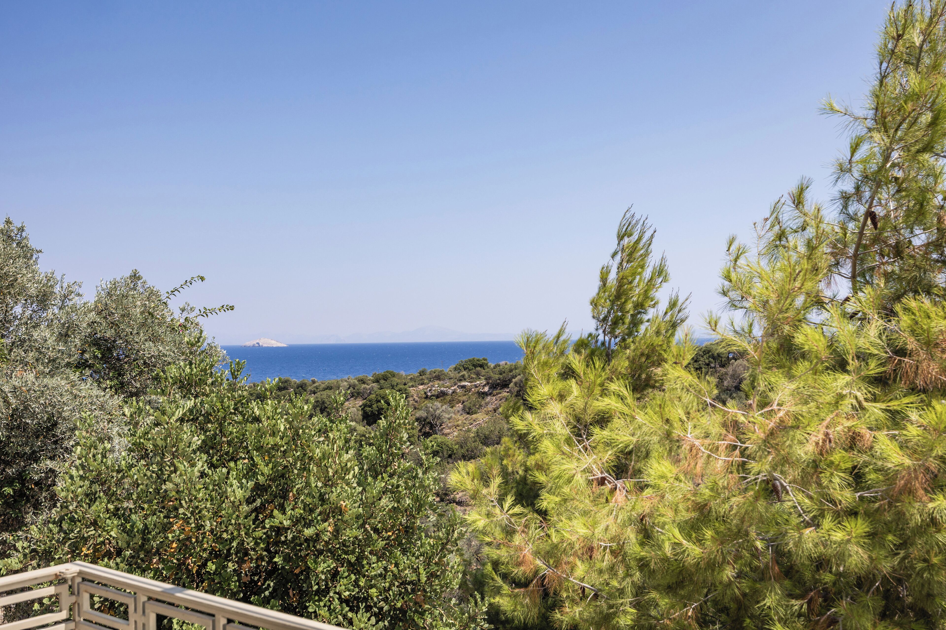 A coastal landscape with dense greenery and a clear view of the sea.