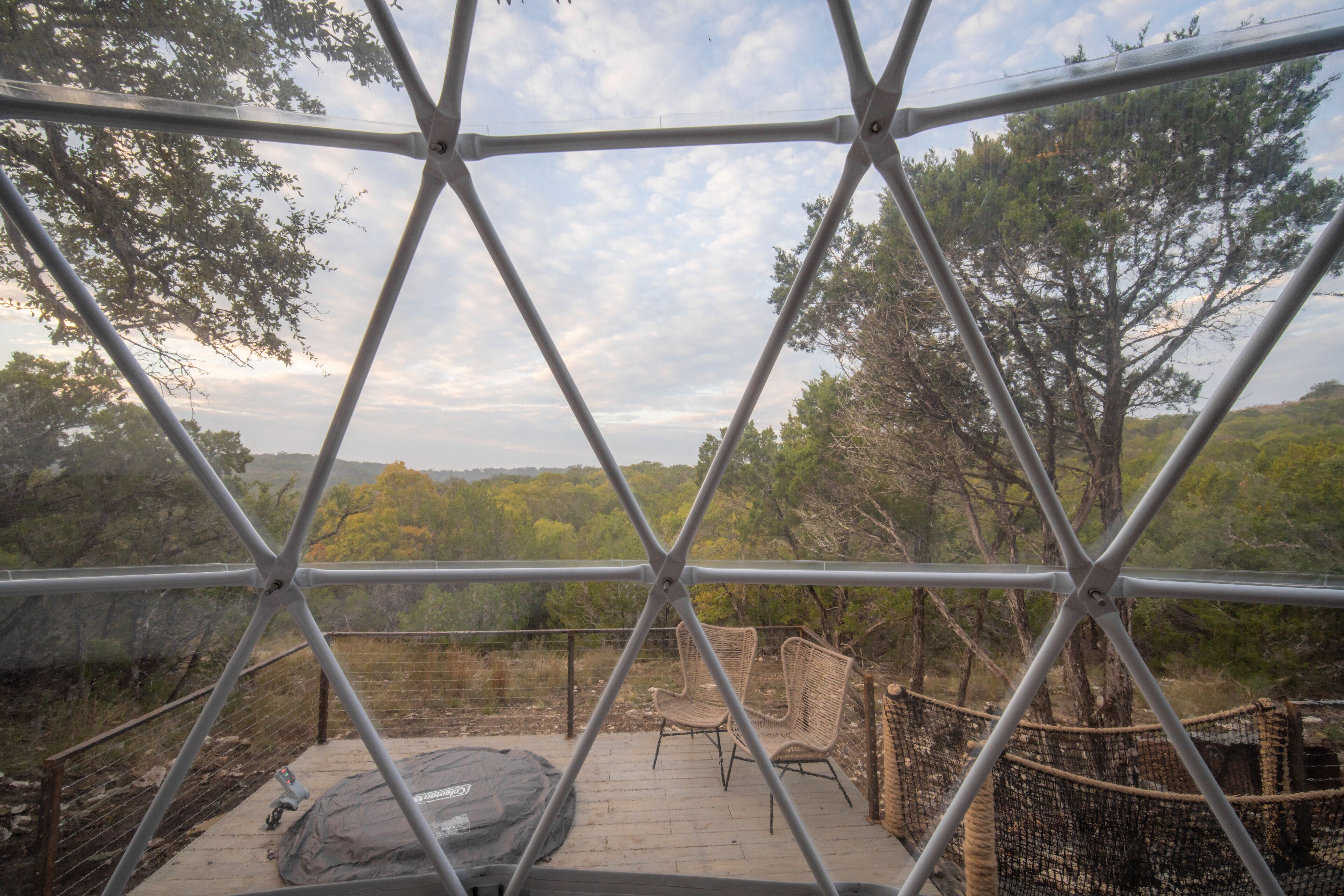 A geodesic dome structure with a view of a forested landscape.