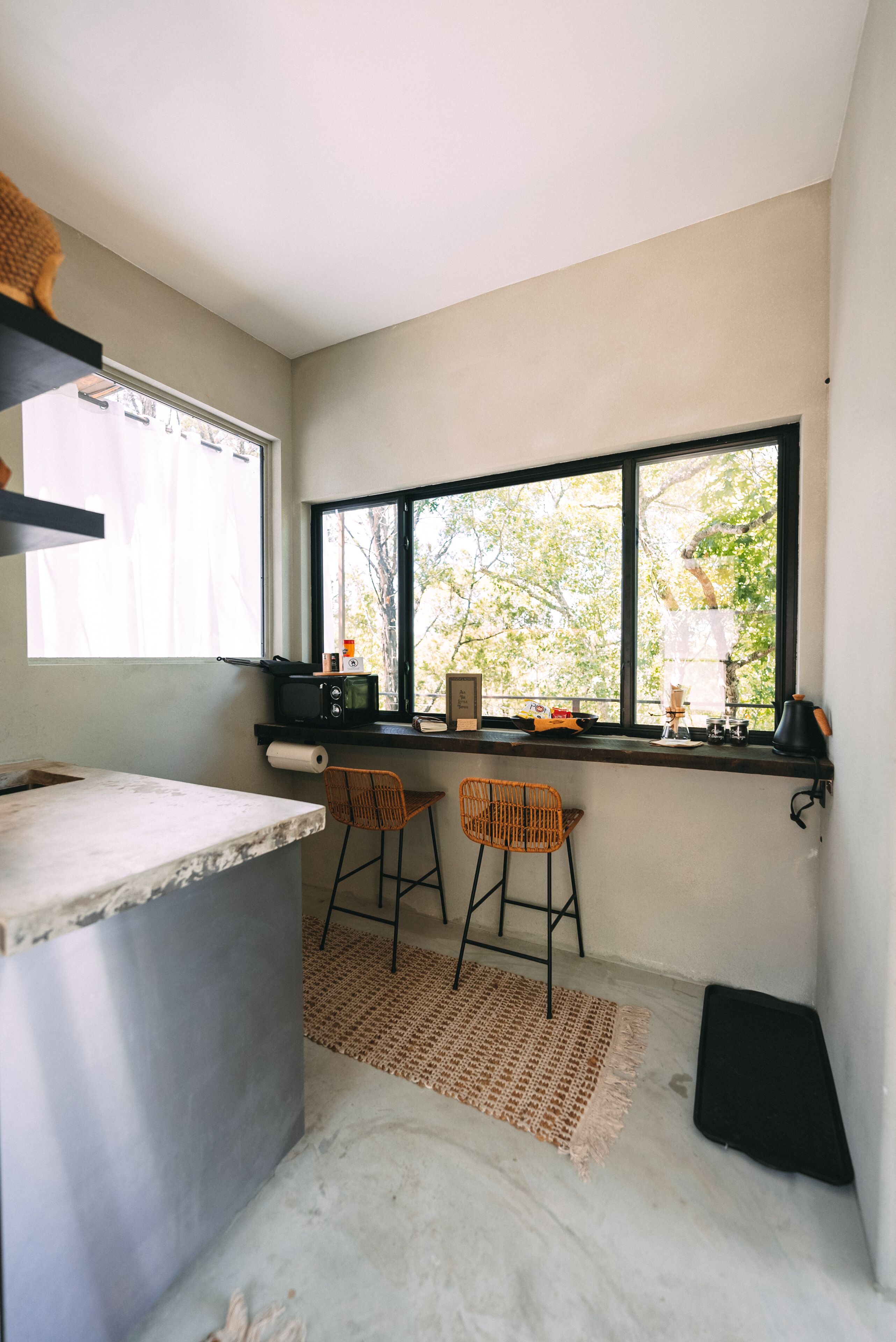 Cocina compacta con ventana, microondas, una mesita y dos sillas.