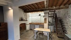 Een rustieke keuken met een stenen muur, houten balken en een houten tafel met stoelen.