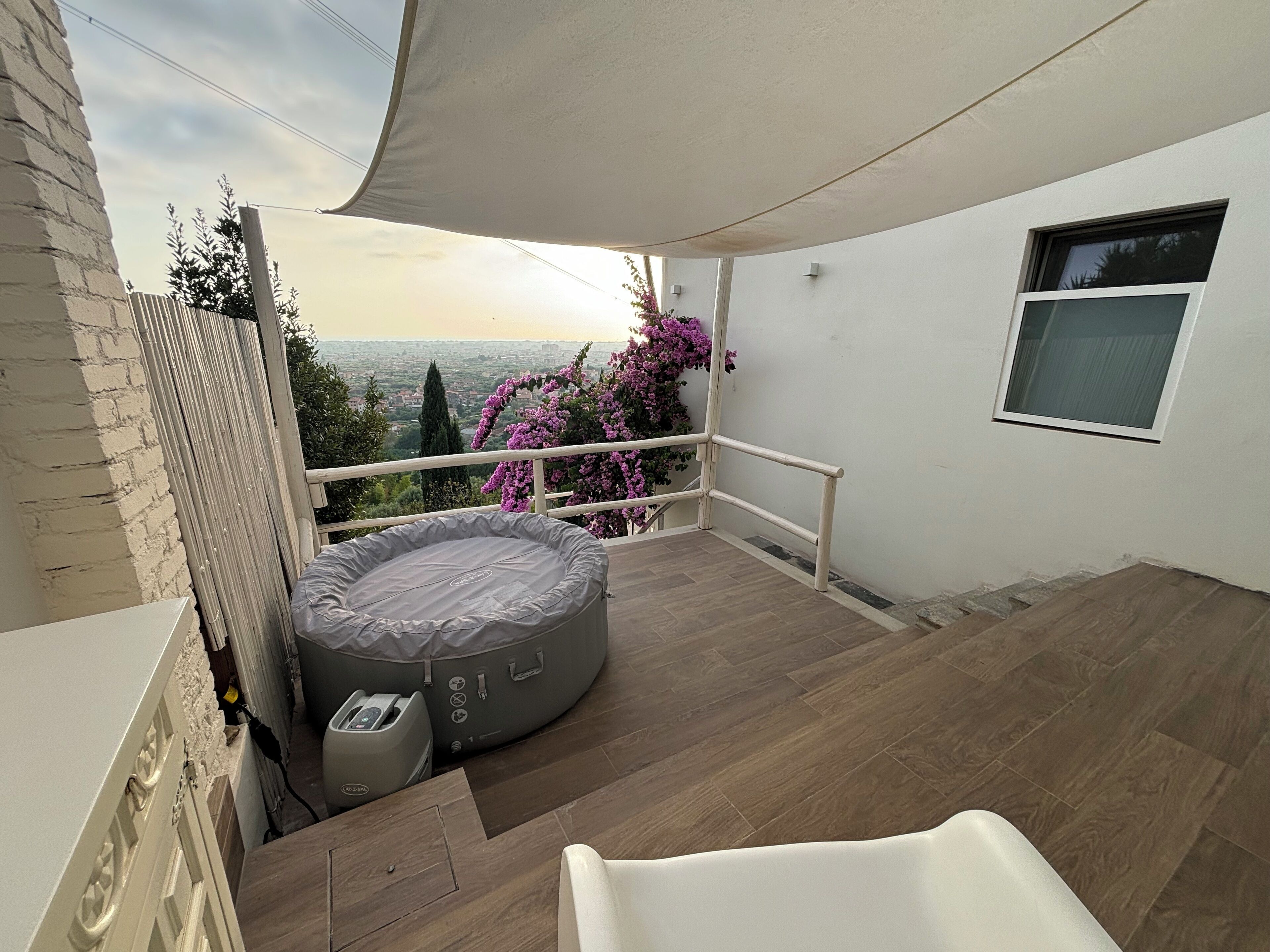 Un balcon avec vue sur la ville, un petit lit rond et une fenêtre.