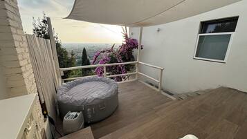 Un balcon avec vue sur la ville, un petit lit rond et une fenêtre.