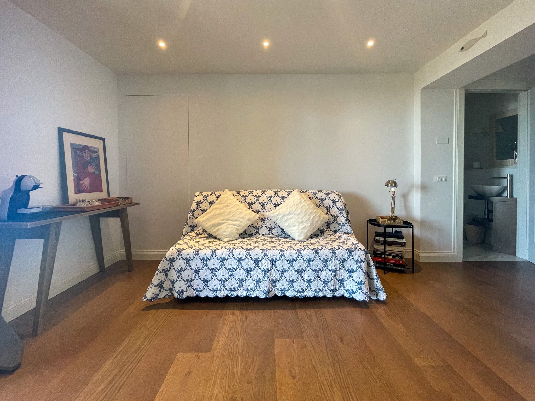 Un dormitorio con una cama, una mesita de noche, una lámpara y un cuadro en la pared.