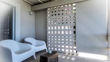 Un espace extérieur moderne aménagé avec deux chaises blanches et un banc en bois.