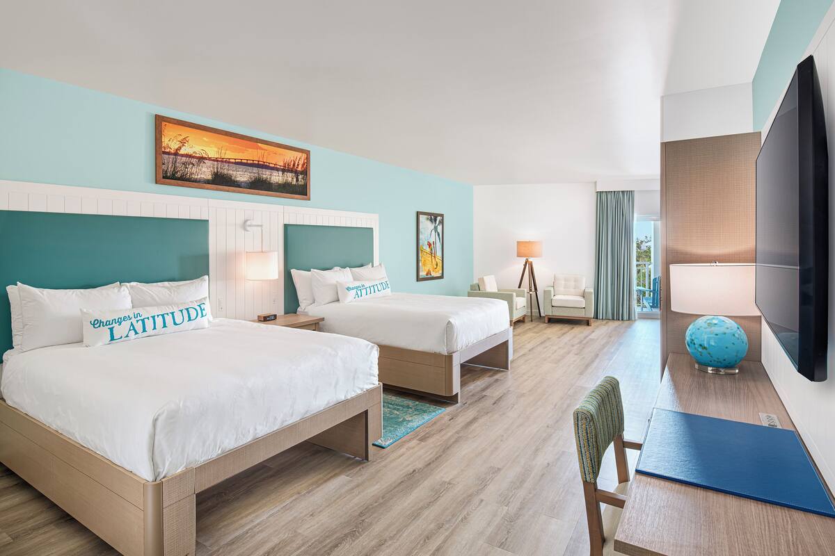 Une chambre d’hôtel avec deux lits, un bureau, une télévision et une vue sur l’extérieur.