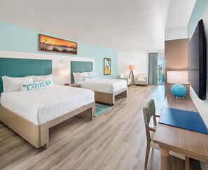 A hotel room with two beds, a desk, a TV, and a view of the outdoors.