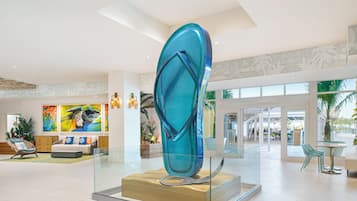 Een moderne lobby met een grote glaskunstinstallatie, een zithoek met een bank en stoelen, en uitzicht op het buitengebied door grote ramen.