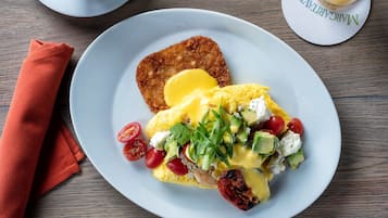 A plate of breakfast with eggs, avocado, and cherry tomatoes.