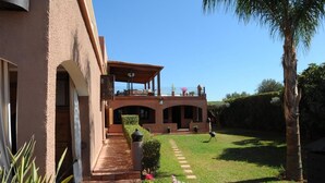 A two-story building with a covered patio and a well-maintained lawn. - Villa Tata Marie Marrakech (Marrakech-Safi)