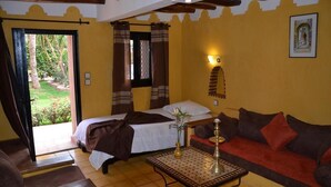 A room with a bed, a sofa, a table with a decorative item, and a window with curtains. - Villa Tata Marie Marrakech (Marrakech-Safi)