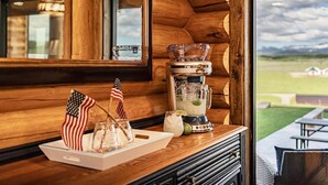 A wooden cabin interior with a wooden table holding a cocktail shaker, glasses, and American flags. - Luxe Log Cabin: Teton Views, Huge Patio, & Hot Tub (Tetonia)