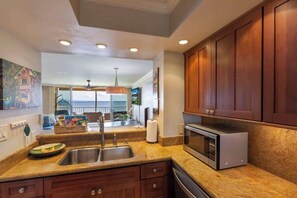 A kitchen with granite countertops, stainless steel appliances, wooden cabinets, and a view to the outside.