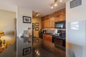 A compact kitchen with wooden cabinets, a microwave, a stove, and a refrigerator.