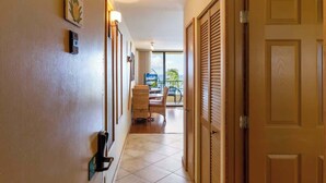 Un couloir d’hôtel avec une porte en bois, un luminaire fixé au mur et une vue sur l’espace extérieur.
