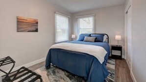A bedroom with a bed, two bedside tables, a chair, and a painting on the wall. - Renovated Home in Central Point (Central Point)