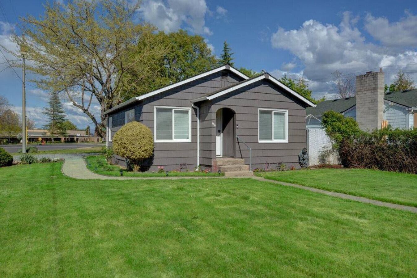 A single-story house with a front porch, a small front yard, and a well-maintained lawn.