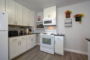 A modern kitchen with white cabinetry, a built-in oven, and a microwave.