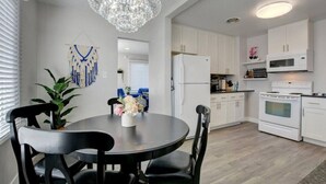 A modern kitchen with white cabinets, a white refrigerator, a white stove, and a microwave. There is a chandelier above the dining table. - Renovated Home in Central Point (Central Point)